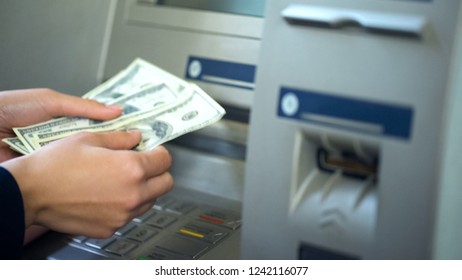 Woman counting dollars withdrawn from ATM, 24h service, easy banking operation - Shutterstock ID 1242116077