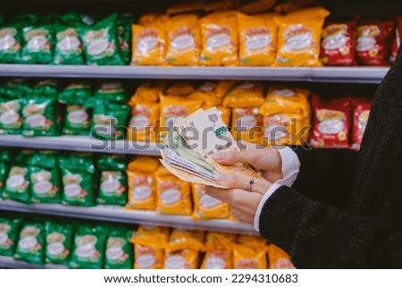 Woman counting money -Argentine pesos- in the supermarket.