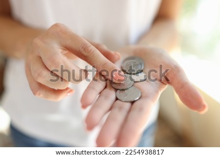 Woman counting small coins in her hands close-up. Cheap price, saving money and poverty concept.