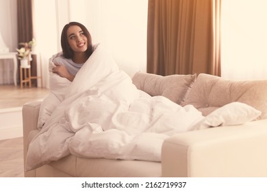 Woman covered in blanket resting on sofa