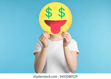 Woman covering face with dollar signs instead of eyes on light blue background - Powered by Shutterstock