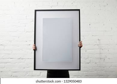 Woman Covering Face While Standing And Holding Blank Black Frame 