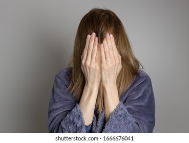 Mujer cubriéndose la cara con las manos y usando un albornoz