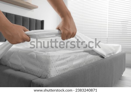 Woman covering mattress with protector indoors, closeup
