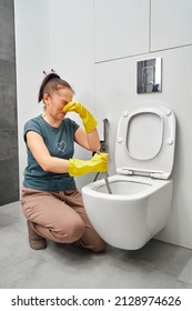 Woman Covering Nose To Avoid Bad Smell While Cleaning A Smelly Toilet Bowl