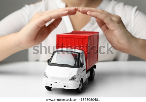 Woman covering toy truck at white table, closeup.\
Logistics and wholesale\
concept