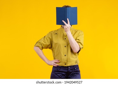 Woman covers her face with a book. Portrait of a girl without a face. Concept - selling books. Literature store. Girl with a book on a yellow background.  Woman reading a book while standing - Powered by Shutterstock