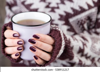 Woman in cozy sweater holding a cup of tea