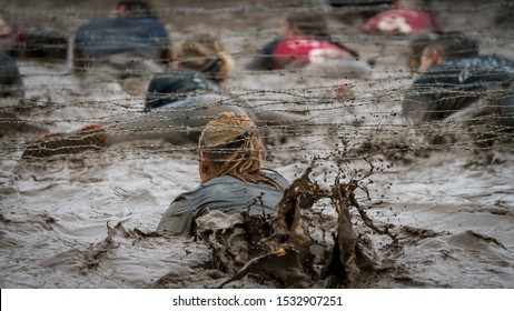 A Woman Crawling Under Barbed Wire At A Mud Run