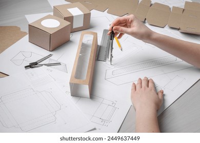 Woman creating packaging design at light wooden table, closeup - Powered by Shutterstock