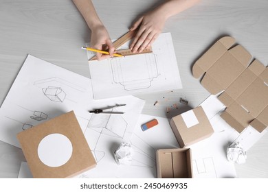 Woman creating packaging design at light wooden table, top view - Powered by Shutterstock