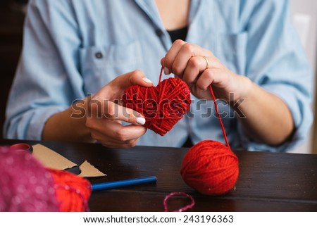 Woman creating red woolen heart