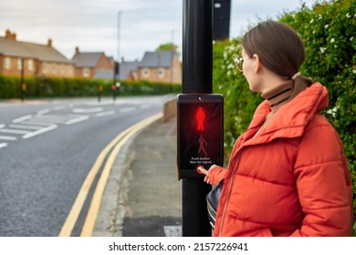 A woman crosses the road by pressing a button at a pedestrian traffic light. A new generation of traffic lights. The concept of a safe city. Traffic rules for children.