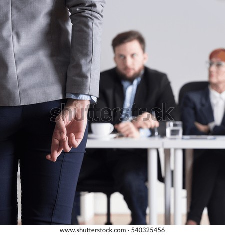 Woman crossing fingers during jobinterview and three businesspeople