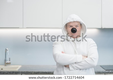 Woman with crossing hands fooling around at home during coronavirus quarantine, dressed up in a funny protective suit with a pan cover