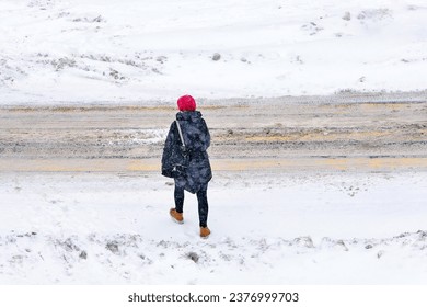 Woman crossing road during blizzard, low visibility in winter season. Woman walking in snowy day view form above. Female crossing road, extreme winter weather. Alone woman walk during snow storm