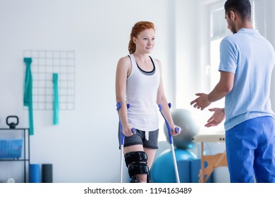 Woman with crutches during rehabilitation with helpful physiotherapist