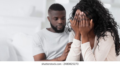 A woman is crying while her partner comforts her. She is covering her face with her hands and he is putting his arm around . - Powered by Shutterstock