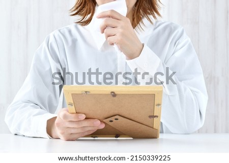 Woman crying while looking at photograph frame