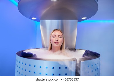 Woman in cryosauna booth for whole body cryotherapy. Caucasian female in freezing chamber with nitrogen vapors.