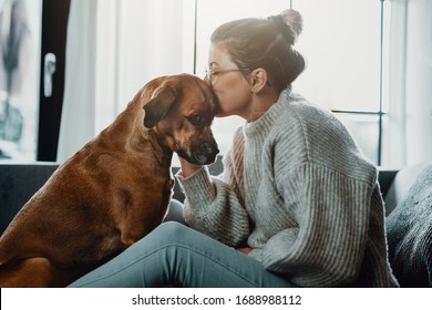Woman cuddles, plays with her dog at home because of the corona virus pandemic covid-19
