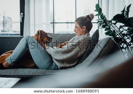 Woman cuddles, plays with her dog at home because of the corona virus pandemic covid-19 Stock photo © 