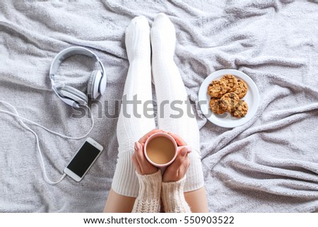 Woman with cup of coffee sitting on the bed