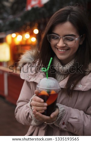 Woman with cup of mulled wine at winter fair