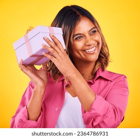 Woman, curious and excited with gift, smile and birthday on a yellow studio background. Person, happy girl and model with a ribbon, present and box with package, surprise and thinking with giveaway - Shutterstock ID 2364786931