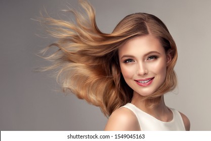 Woman with curly beautiful hair  on gray background. Girl with beauty a pleasant smile. Short wavy  hairstyle