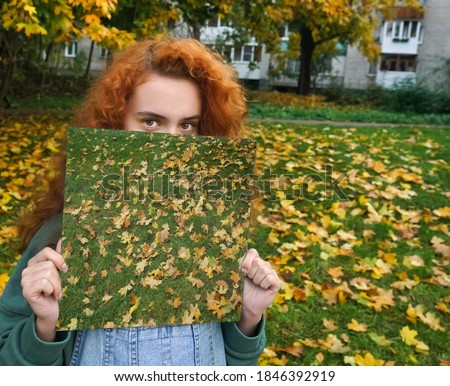 woman with curly red hair holding mirror with reflection. Autumn season.