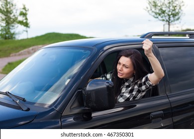 The Woman Is Cussing On Someone And Holding Car Wheel With One Hand And Showing A Fist Of A Black Car.