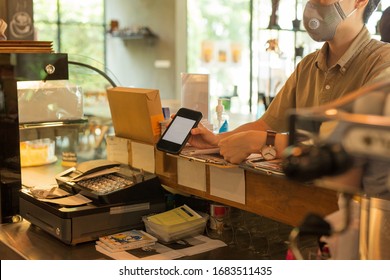 Woman Customer With Protective Mask Paying Bill By Cell Phone In Cafe