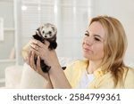 Woman with cute ferret at home. Domestic pet