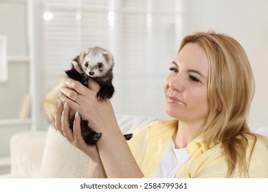 Woman with cute ferret at home. Domestic pet
