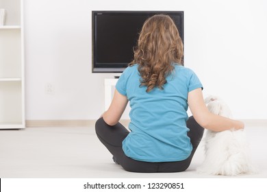 Woman And Cute White Maltese Dog Watching TV Together At Home