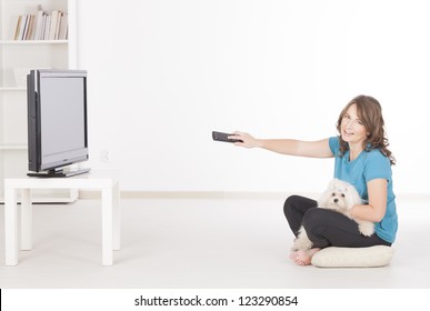 Woman And Cute White Maltese Dog Watching TV Together At Home