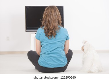 Woman And Cute White Maltese Dog Watching TV Together At Home