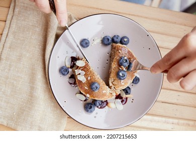 Woman With Cutlery Eating Traditional Pancakes With Fresh Blueberries And Agave Syrup On A Plate. Breakfast Outside On The Terrace.