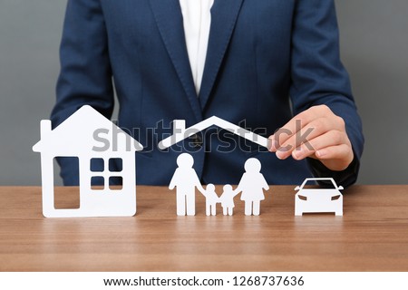 Woman with cutout paper family, house and car at table, closeup. Life insurance concept