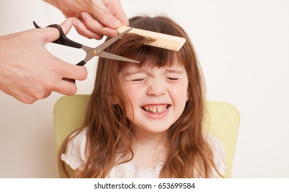 Woman cuts the baby hair. The girl is afraid to cut hair. He closed his eyes with fear. The background image place for text.