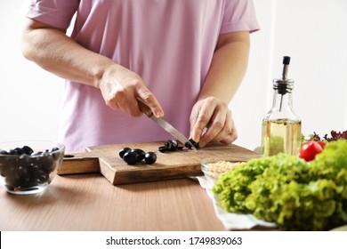 Woman Cuts Black Olives. The Process Of Making Salad