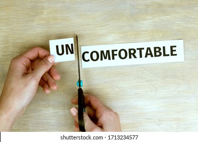 Woman cuts by scissors word "uncomfortable", written on paper, so that the word "comfortable" is obtained. 
