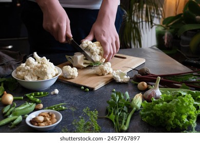 A woman cuts fresh cauliflower at the table - Powered by Shutterstock