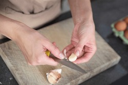A Woman Cuts Garlic With A Knife Close-up. Cutting Garlic For Salad Or As An Aromatic Spice For Meat.