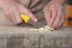 A Woman Cuts Garlic With A Knife Close-up. Cutting Garlic For Salad Or As An Aromatic Spice For Meat.