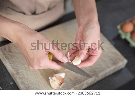 A woman cuts garlic with a knife close-up. Cutting garlic for salad or as an aromatic spice for meat.