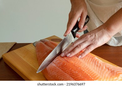 A Woman Cuts Off A Large Piece Of Salmon Fillet. Omega 3, Raw Fish, Cooking Concept. Part Of Body. Day Light.