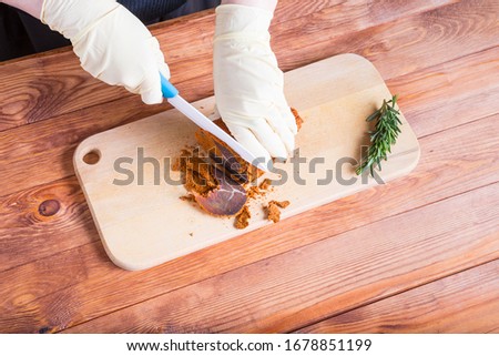 Woman cuts a piece of beef basturma by ceramic knife on a timbered table