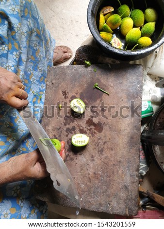 A woman cuts Sri Lankan traditional fruits on a wooden chopping block.